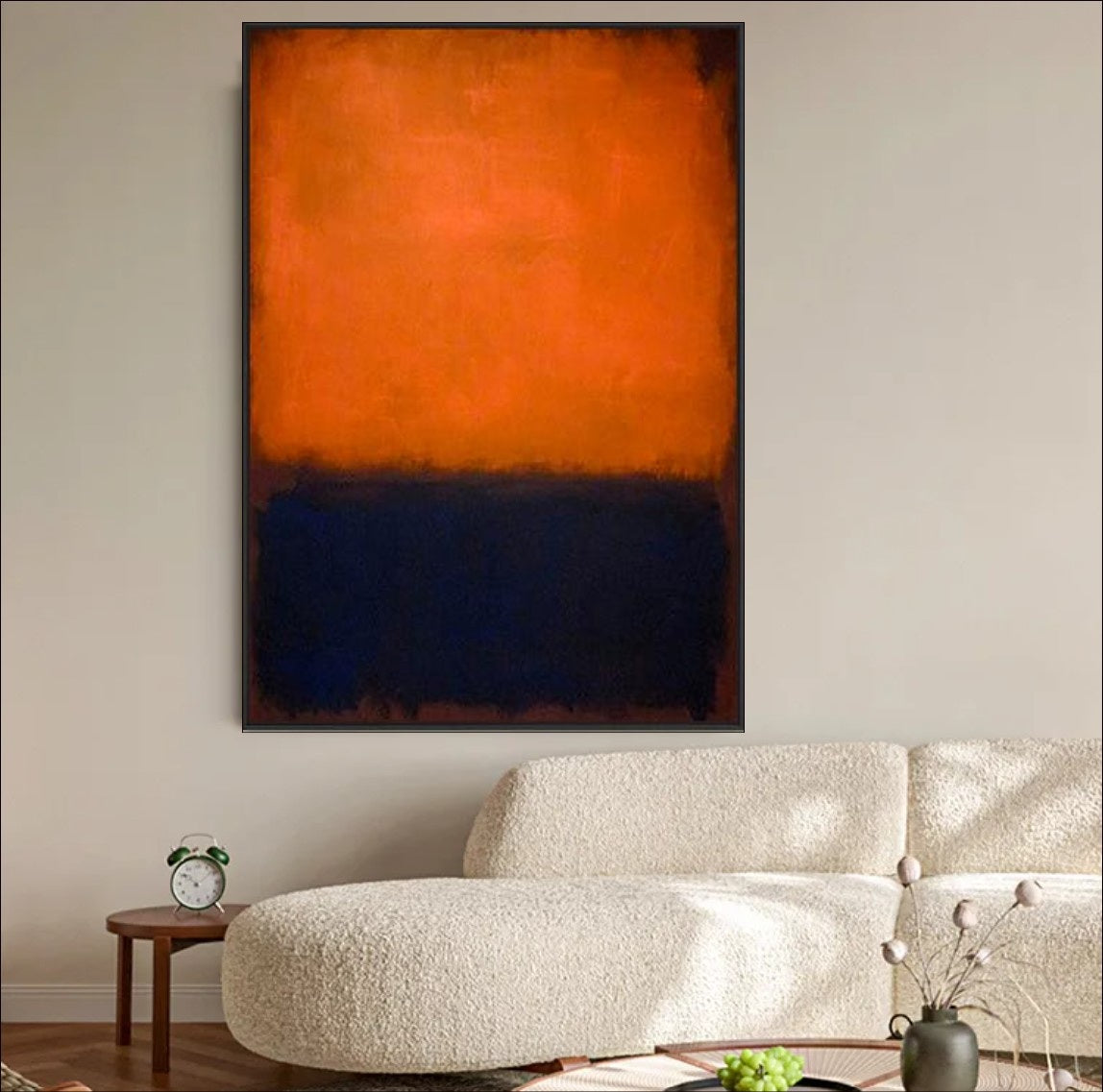 Abstract art piece with orange and black colors on a gray wall, with a lamp and decorative bowl in the foreground.