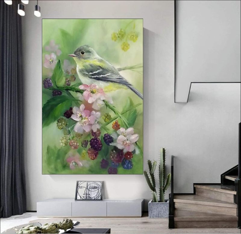 Realistic oil painting of a small grey and yellow songbird perched on a branch with pink blossoms and ripening blackberries against a soft green background.