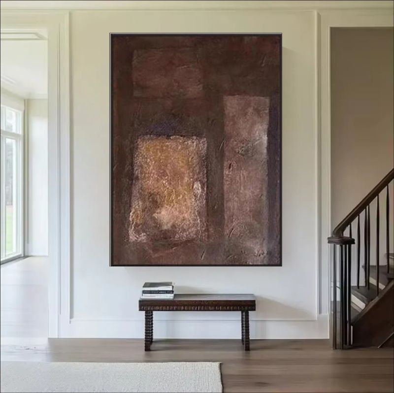 Abstract painting featuring deep brown, rust, and copper block textures hanging above a bed in a modern minimalist room, rustic wall art style.